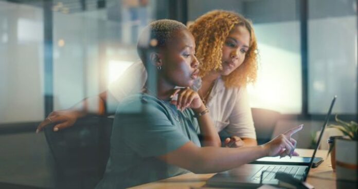 Femmes freelances dans un bureau qui regardent le même écran d'ordinateur.